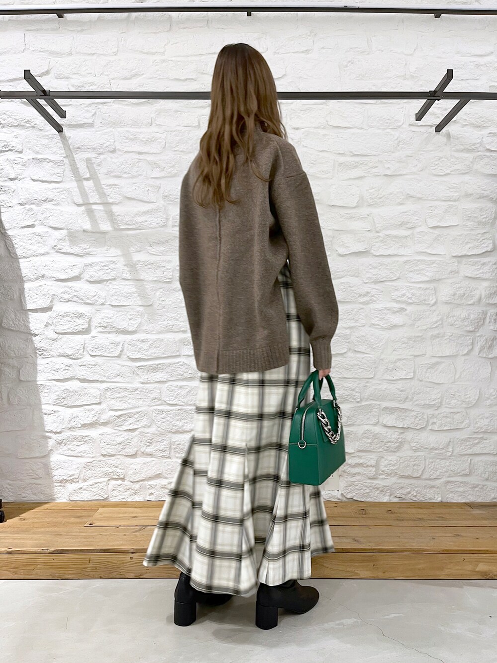 ブラウン系のニット/セーター、ホワイト系のスカート、ブラック系のブーツを着用したレディースの冬コーディネートの4枚目の写真