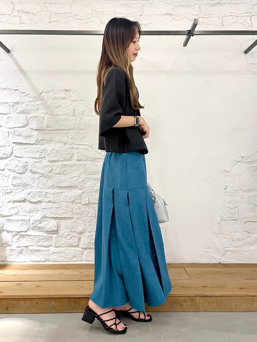 ブラック系のテーラードジャケット、ホワイト系のタンクトップ、ブルー系のスカートを着用したレディースの夏コーディネートの2枚目の写真