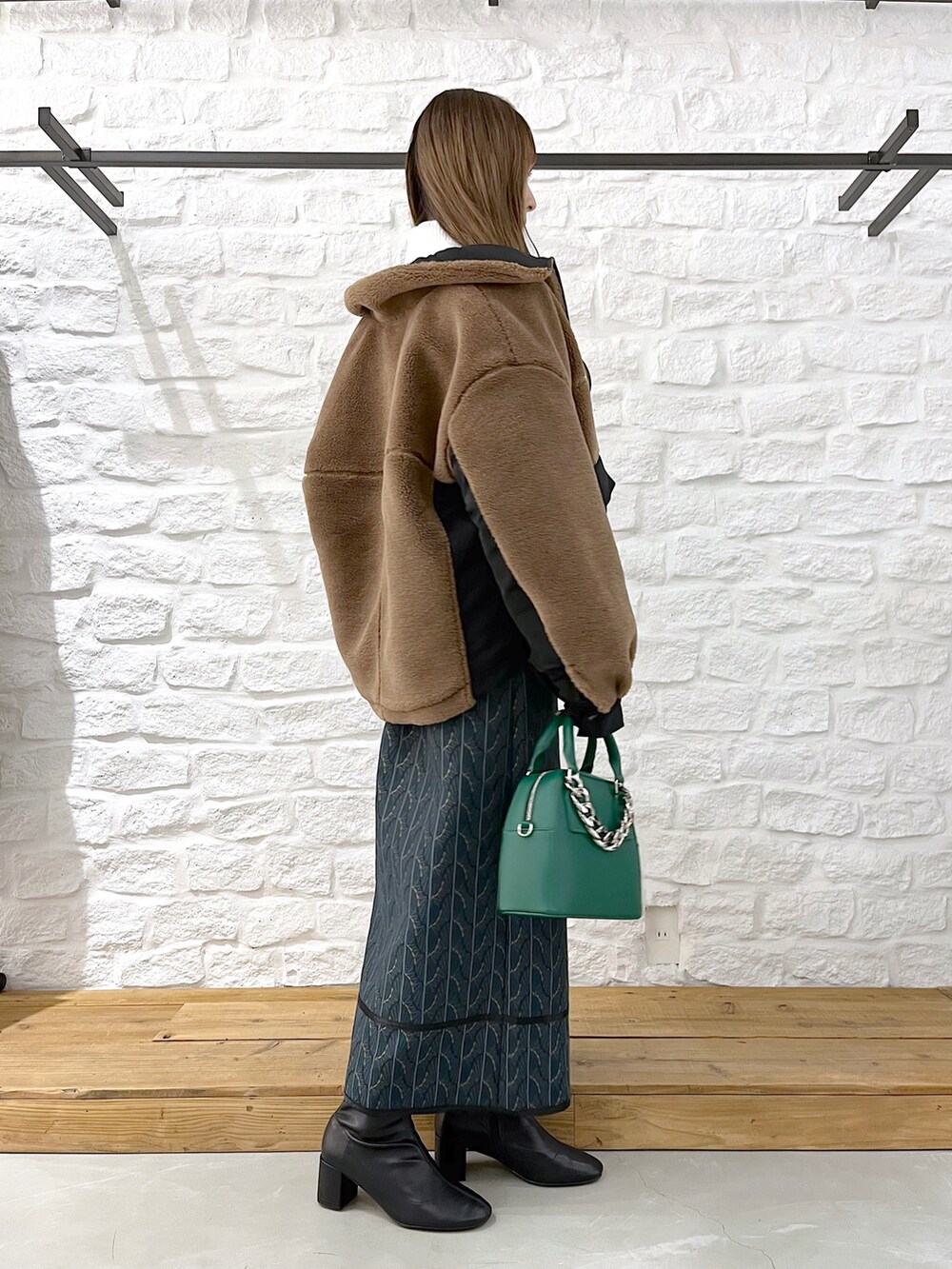 ブラウン系のブルゾン、ホワイト系のニット/セーター、グリーン系のショルダーバッグを着用したレディースの冬コーディネートの3枚目の写真