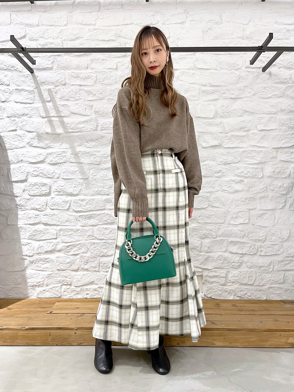 ブラウン系のニット/セーター、ホワイト系のスカート、ブラック系のブーツを着用したレディースの冬コーディネートの2枚目の写真