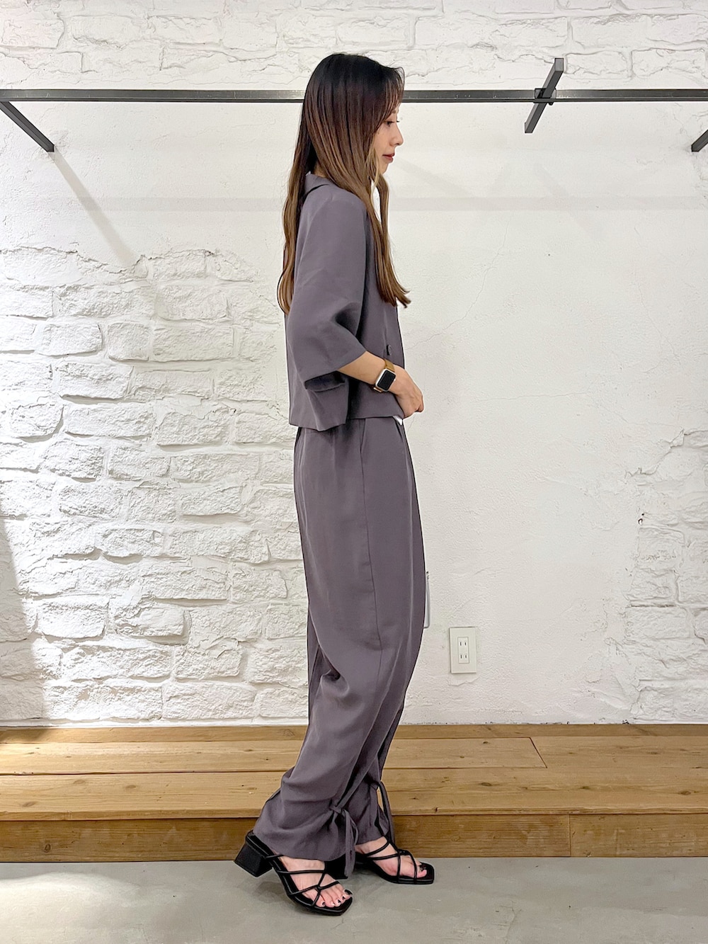 グレー系のテーラードジャケット、ホワイト系のタンクトップ、グレー系のスラックスを着用したレディースの夏コーディネートの3枚目の写真