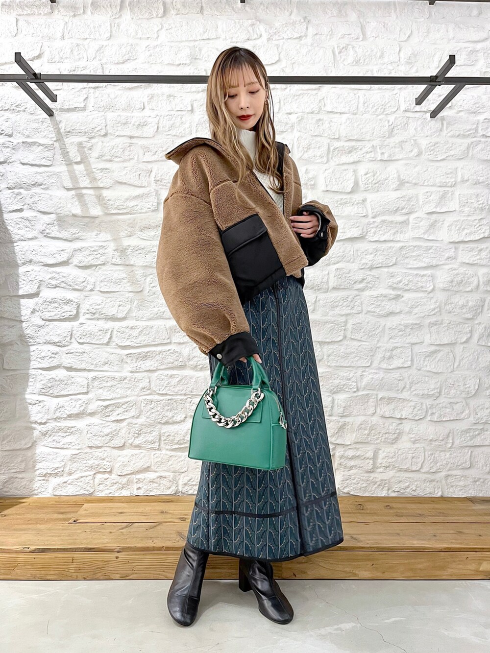 ブラウン系のブルゾン、ホワイト系のニット/セーター、グリーン系のショルダーバッグを着用したレディースの冬コーディネートの2枚目の写真