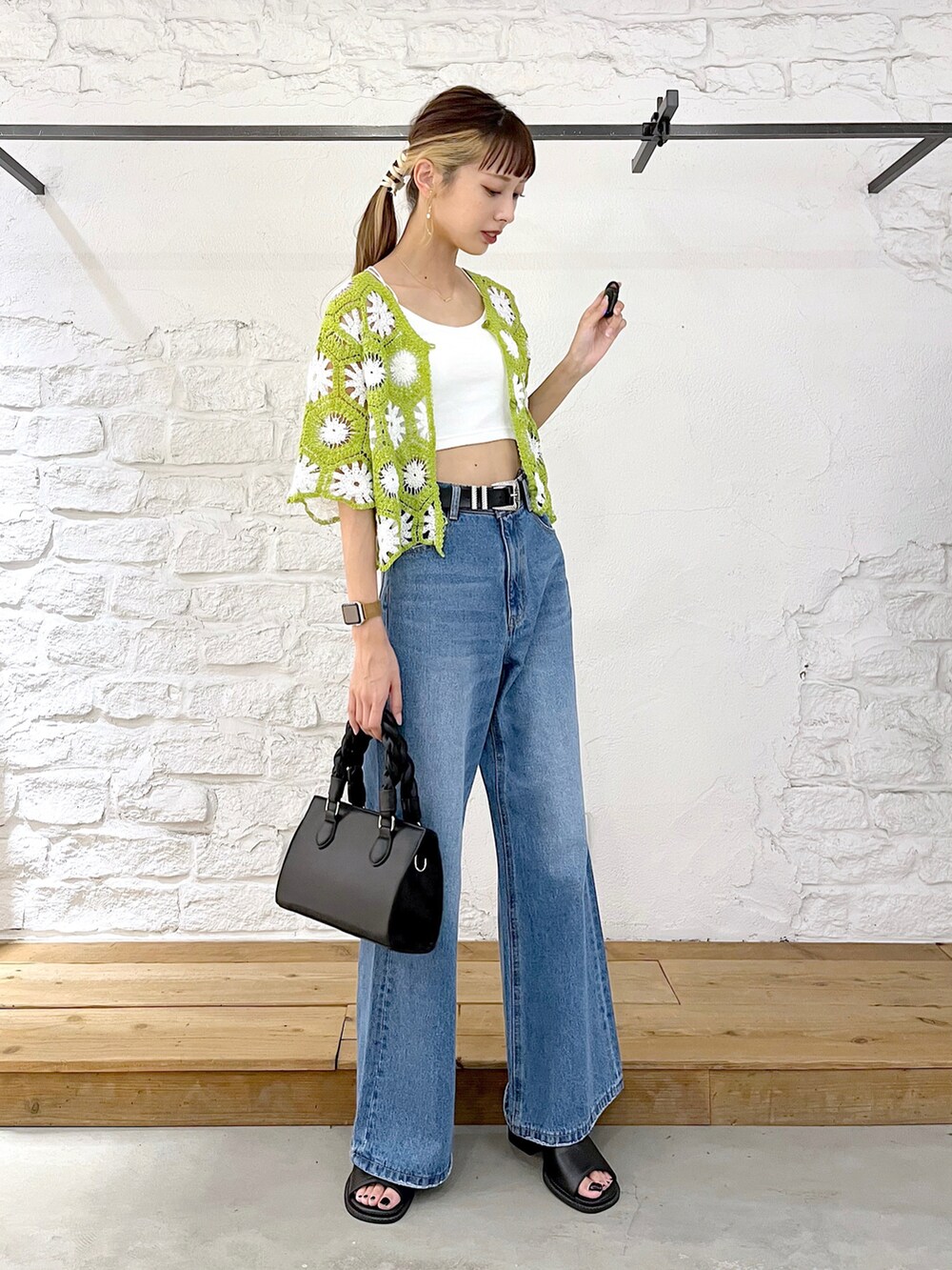グリーン系のカーディガン/ボレロ、ホワイト系のキャミソール、ブルー系のデニムパンツを着用したレディースの夏コーディネートの2枚目の写真