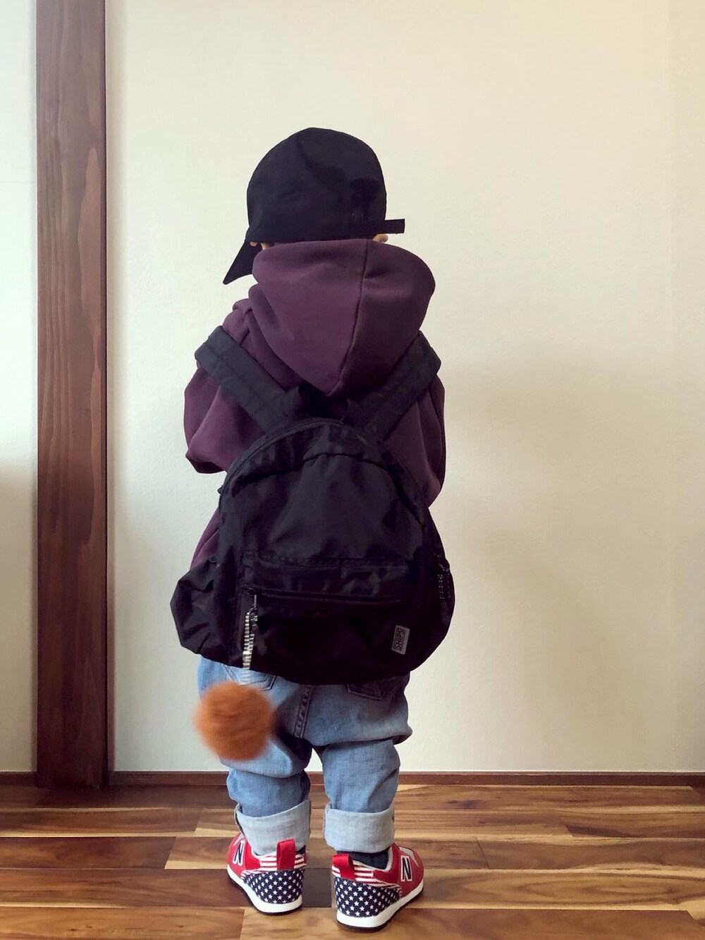 パープル系のスウェット、ブラック系のバックパック/リュック、ブルー系のデニムパンツを着用したキッズの秋コーディネートの2枚目の写真