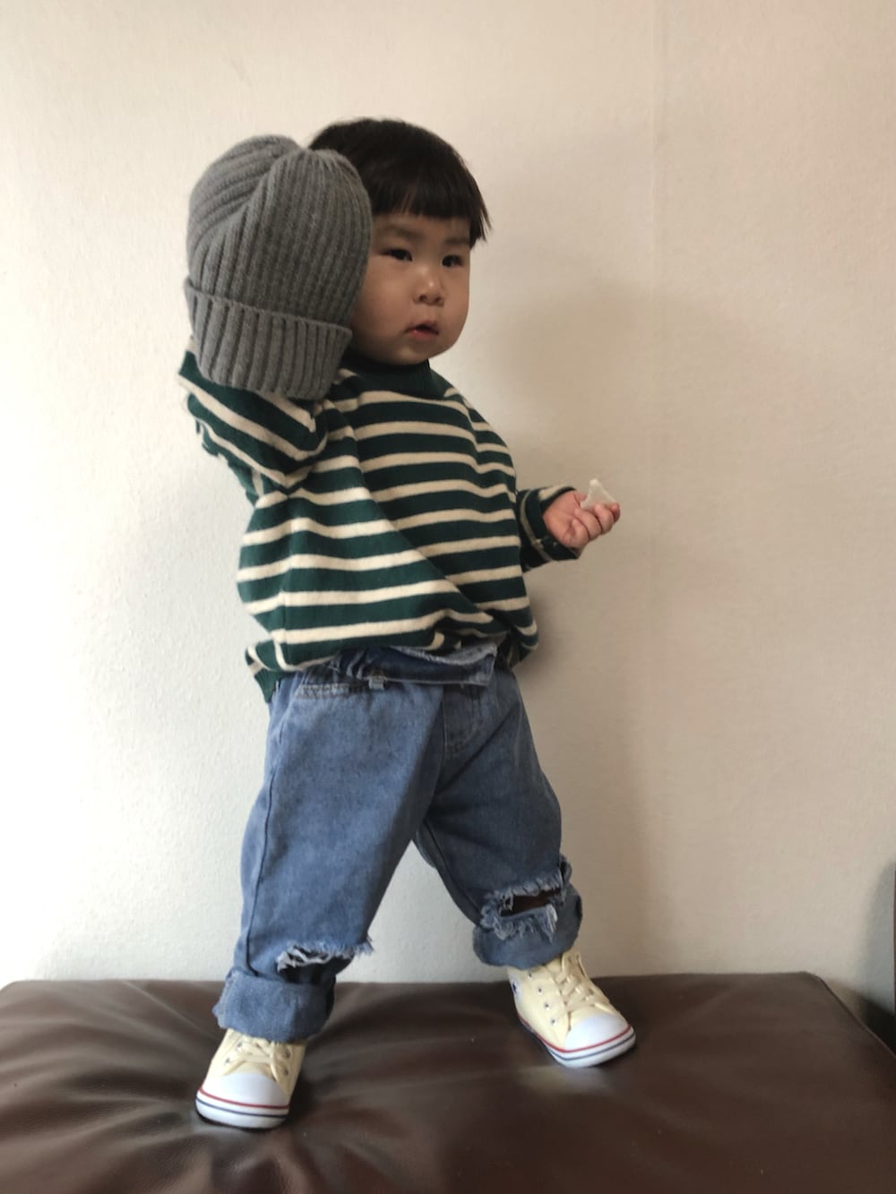 グリーン系のスウェット、ブルー系のデニムパンツ、ホワイト系のスニーカーを着用したキッズの冬コーディネートの2枚目の写真