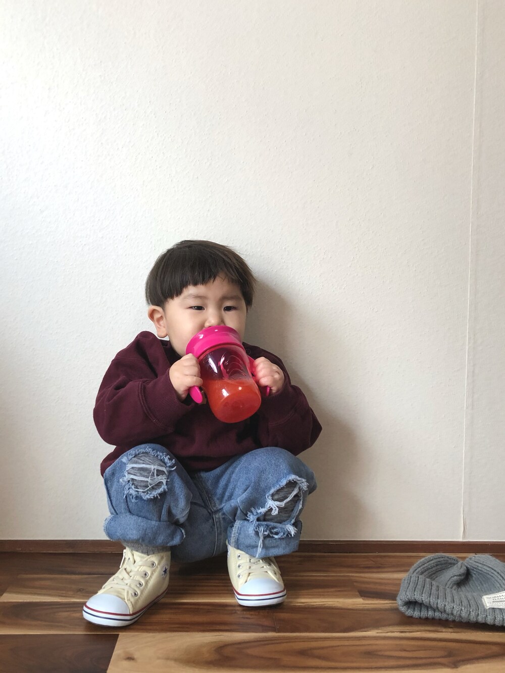 レッド系のスウェット、ベージュ系のTシャツ/カットソー、ブルー系のデニムパンツを着用したキッズの冬コーディネートの2枚目の写真