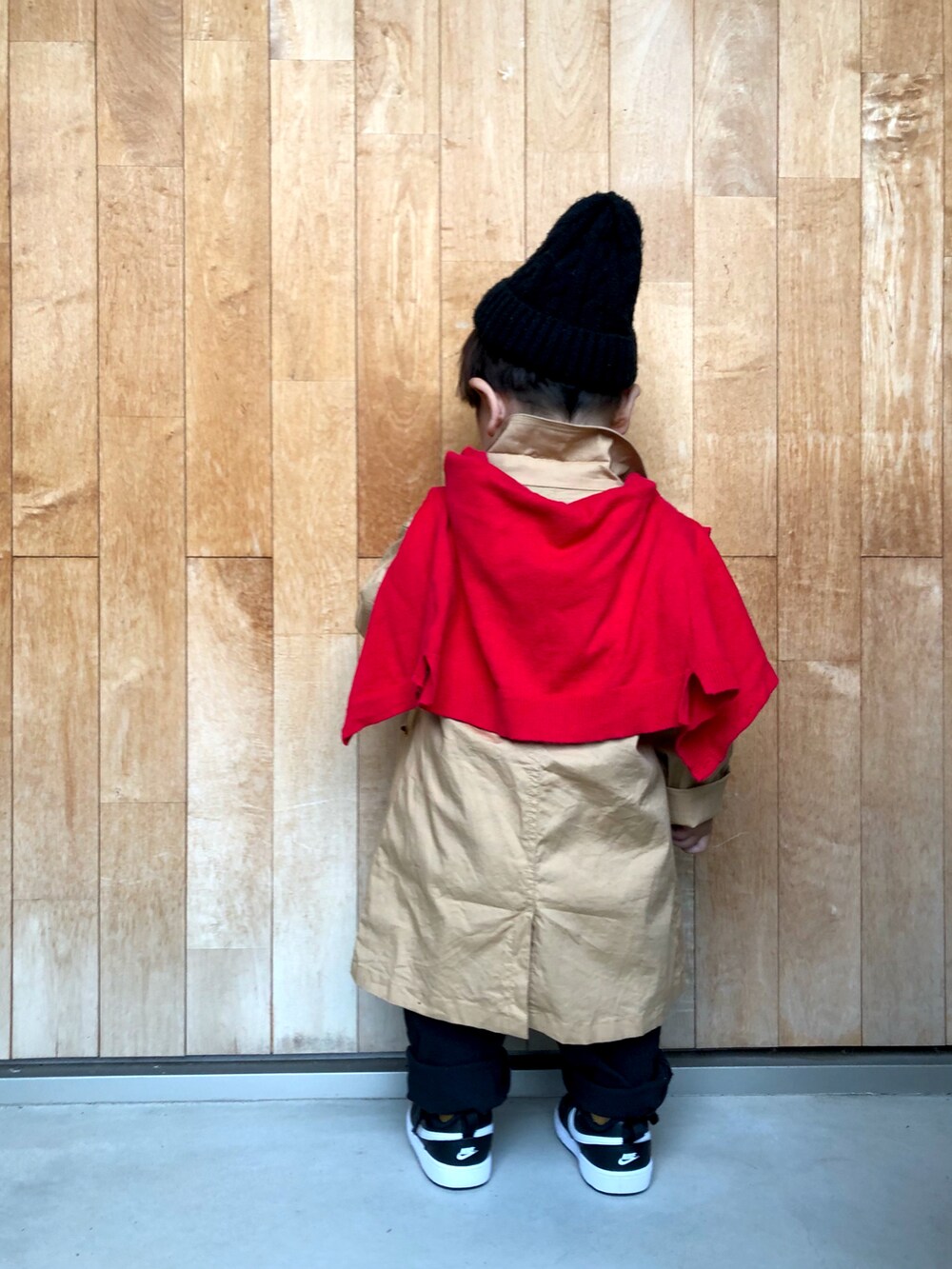 ホワイト系のスウェット、ベージュ系のステンカラーコート、レッド系のカーディガン/ボレロを着用したキッズの春コーディネートの3枚目の写真
