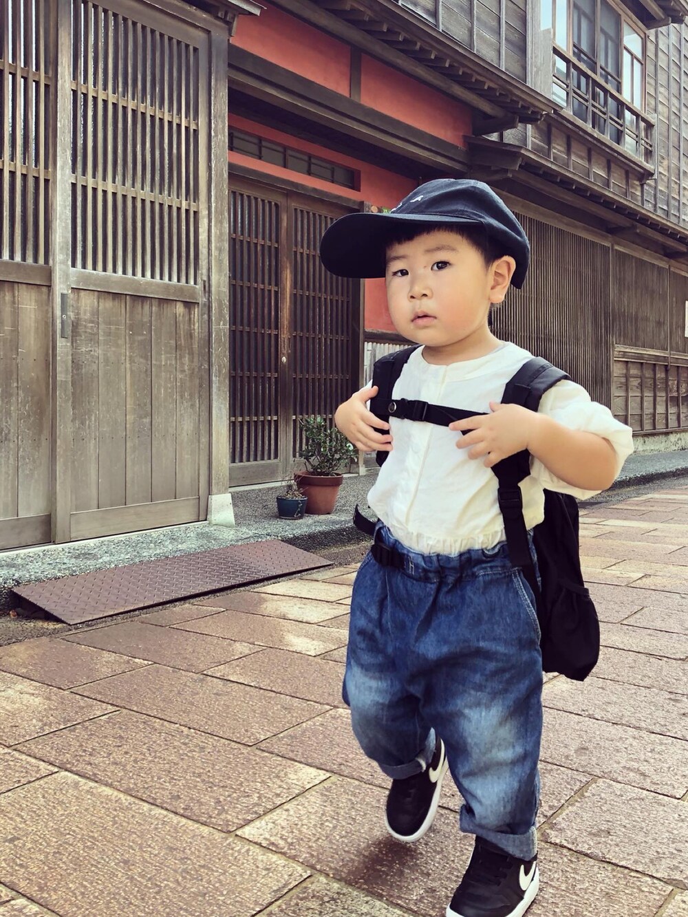 グレー系のニット/セーター、ブラック系のバックパック/リュック、ブルー系のその他パンツを着用したキッズの秋コーディネートの2枚目の写真