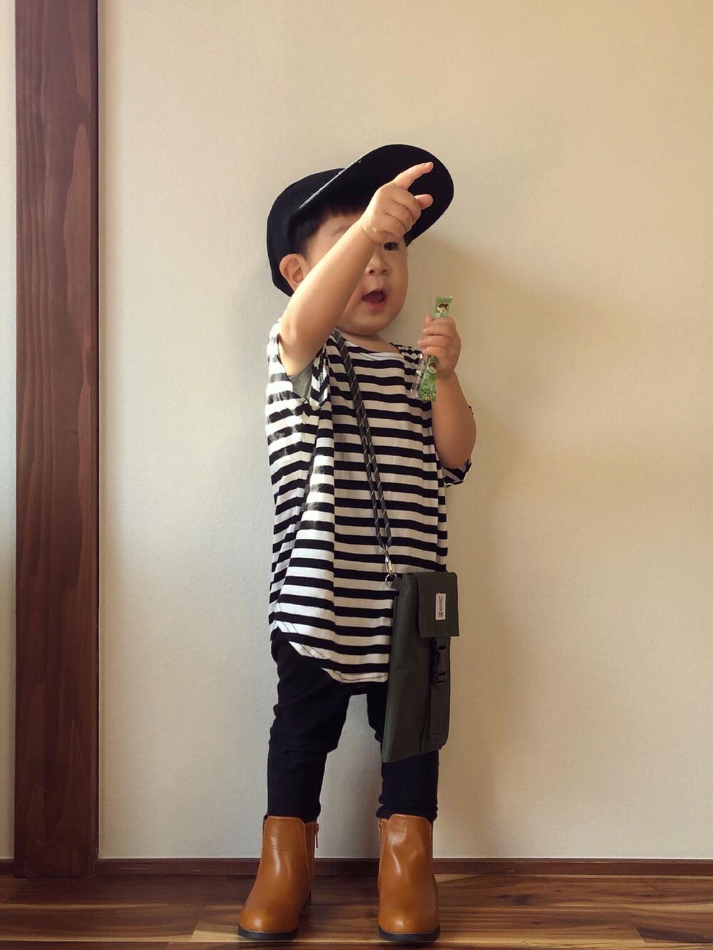 ブラック系のTシャツ/カットソー、イエロー系のブーツ、グリーン系のバッグを着用したキッズの秋コーディネートの3枚目の写真