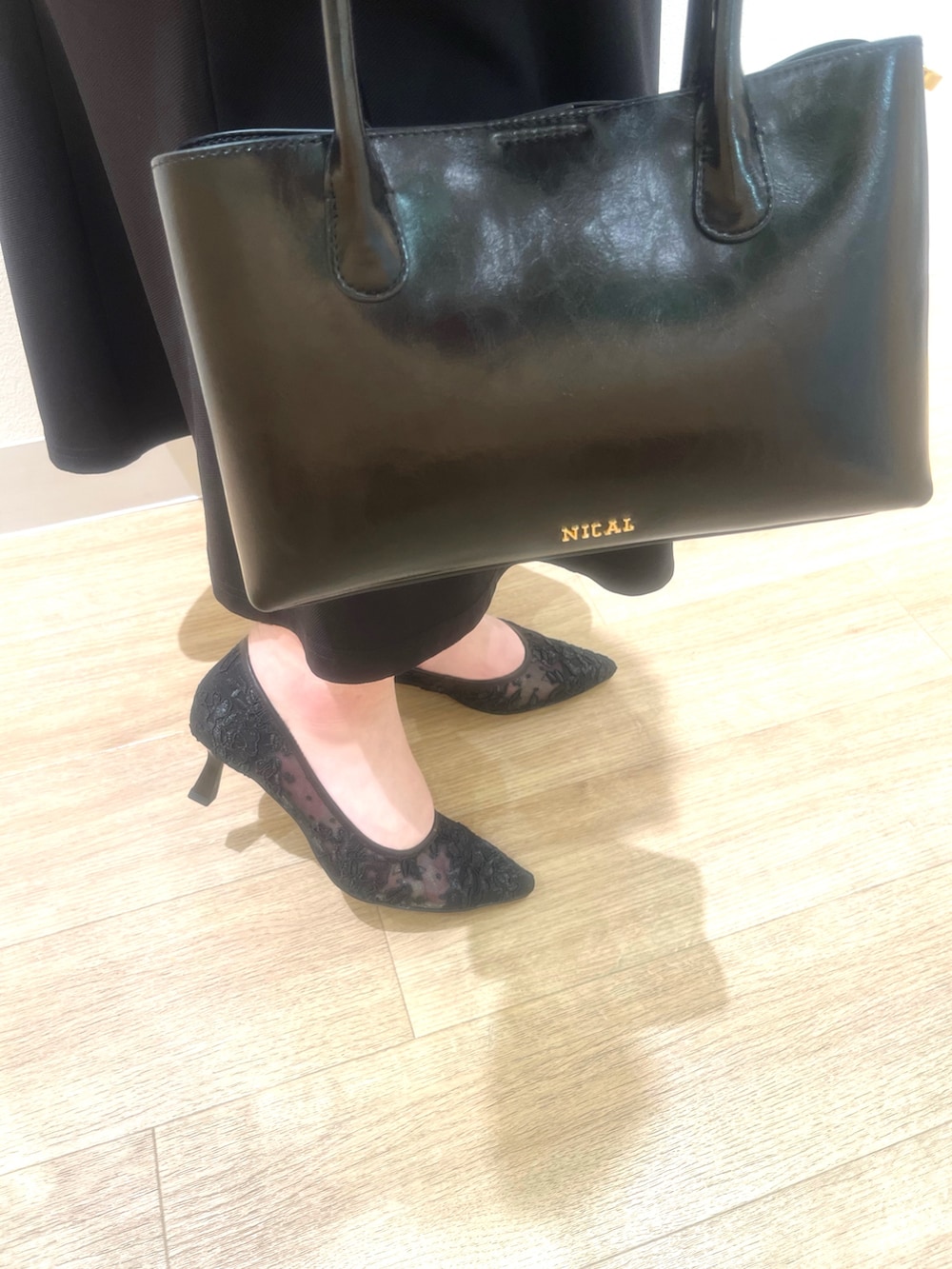 ブラック系のパンプス、ブラック系のバッグを着用したレディースの春コーディネートの2枚目の写真