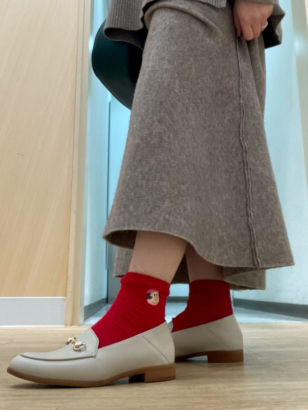 グリーン系のバッグ、ホワイト系のローファーを着用したレディースの冬コーディネートの2枚目の写真