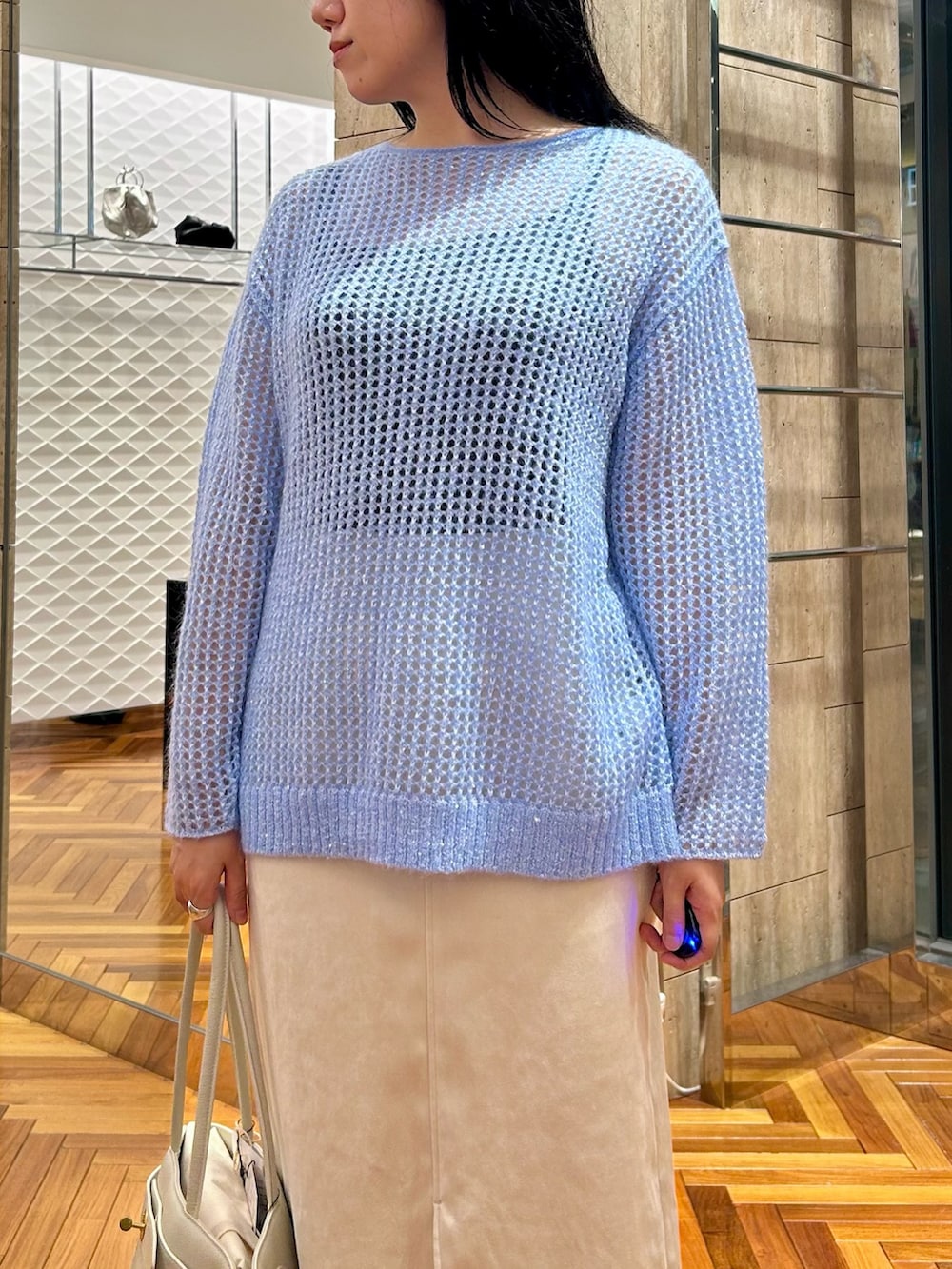 ホワイト系のトートバッグ、ホワイト系のスカート、ブルー系のニット/セーターを着用したレディースの秋コーディネートの4枚目の写真