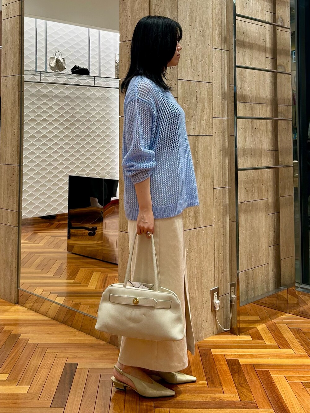 ホワイト系のトートバッグ、ホワイト系のスカート、ブルー系のニット/セーターを着用したレディースの秋コーディネートの2枚目の写真
