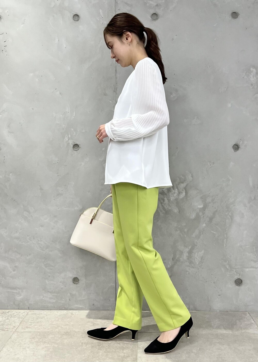 ホワイト系のシャツ/ブラウス、ホワイト系のショルダーバッグ、グリーン系のスラックスを着用したレディースの春コーディネートの2枚目の写真