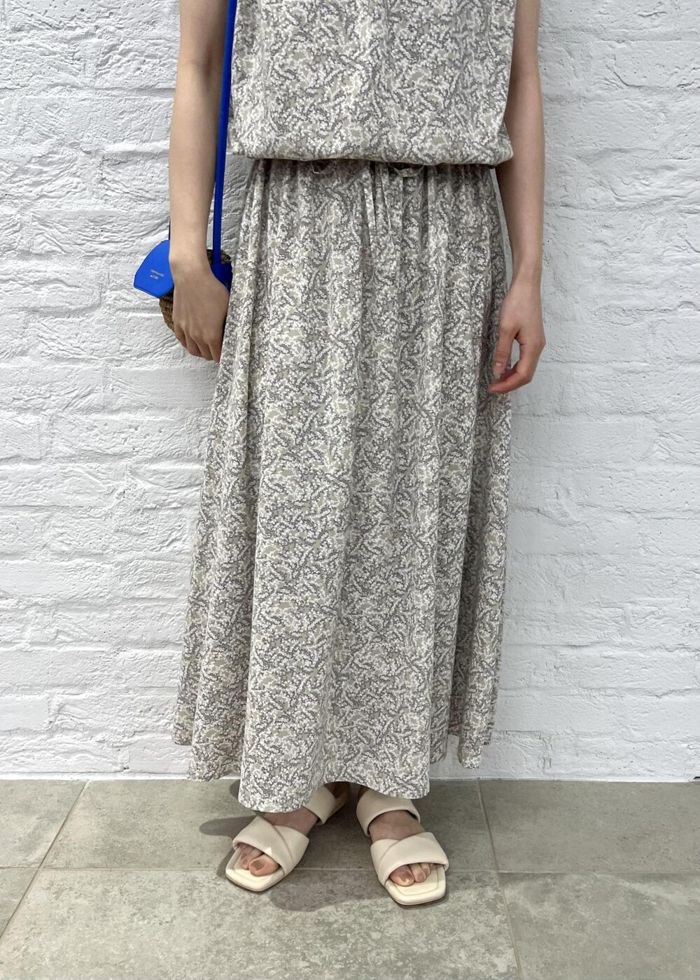 ブルー系のショルダーバッグ、ベージュ系のワンピース、ホワイト系のサンダルを着用したレディースの夏コーディネートの5枚目の写真