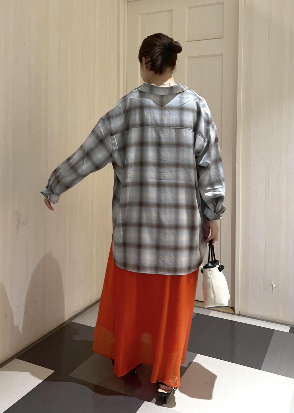 オレンジ系のスカート、ブラック系のタンクトップ、ブラック系のサンダルを着用したレディースの夏コーディネートの5枚目の写真