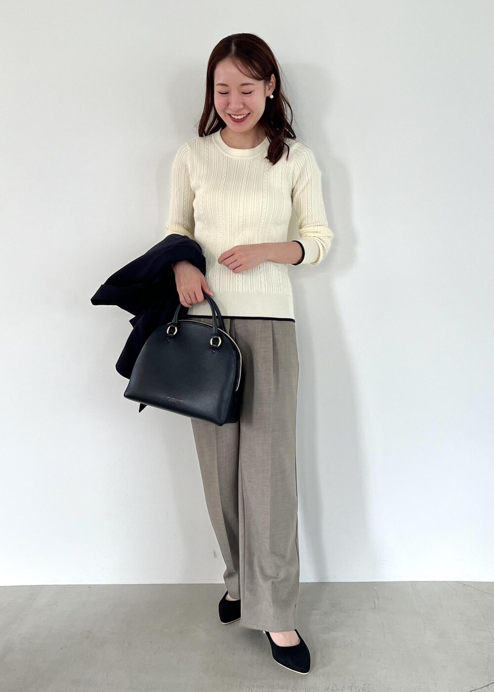 ブラック系のボストンバッグ、ブルー系のテーラードジャケット、ホワイト系のニット/セーターを着用したレディースの秋コーディネートの4枚目の写真