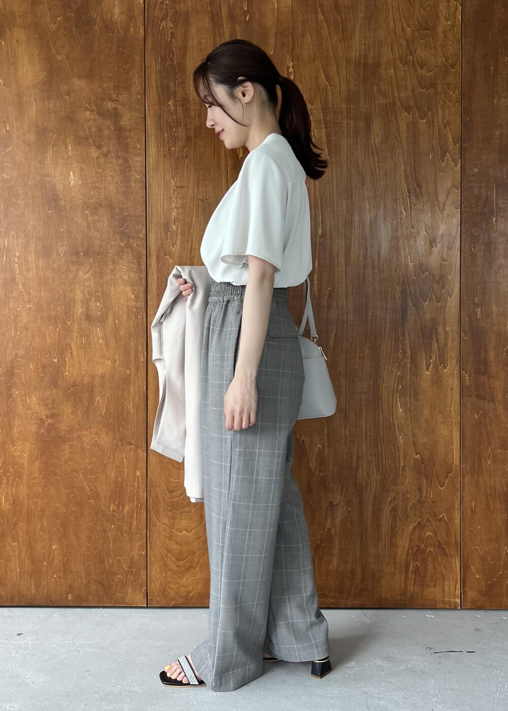 ブラック系のサンダル、ベージュ系のジャンパースカート、ホワイト系のシャツ/ブラウスを着用したレディースの夏コーディネートの2枚目の写真