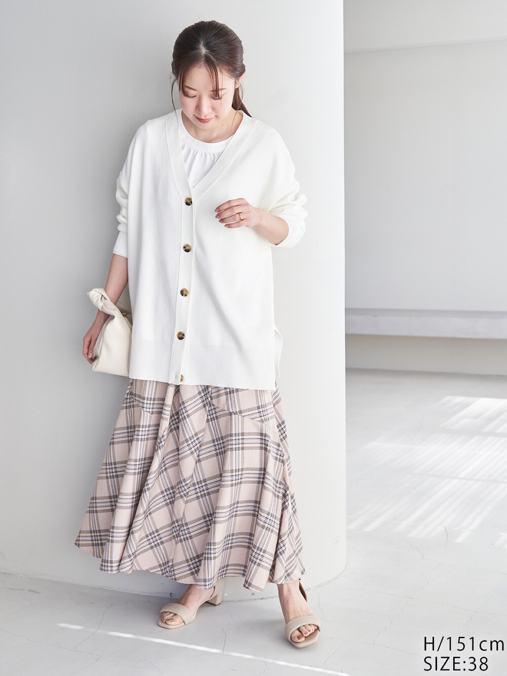 ホワイト系のカーディガン/ボレロ、ホワイト系のショルダーバッグ、ベージュ系のスカートを着用したレディースの冬コーディネートの2枚目の写真