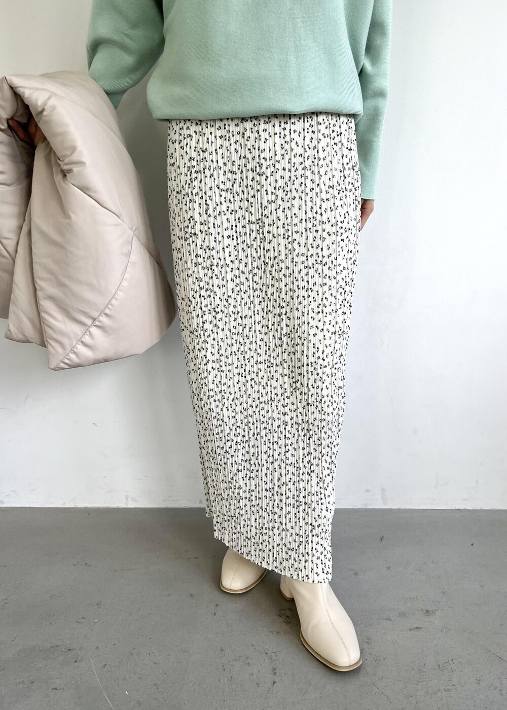 グリーン系のニット/セーター、ホワイト系のブーツ、ホワイト系のスカートを着用したレディースの秋コーディネートの5枚目の写真