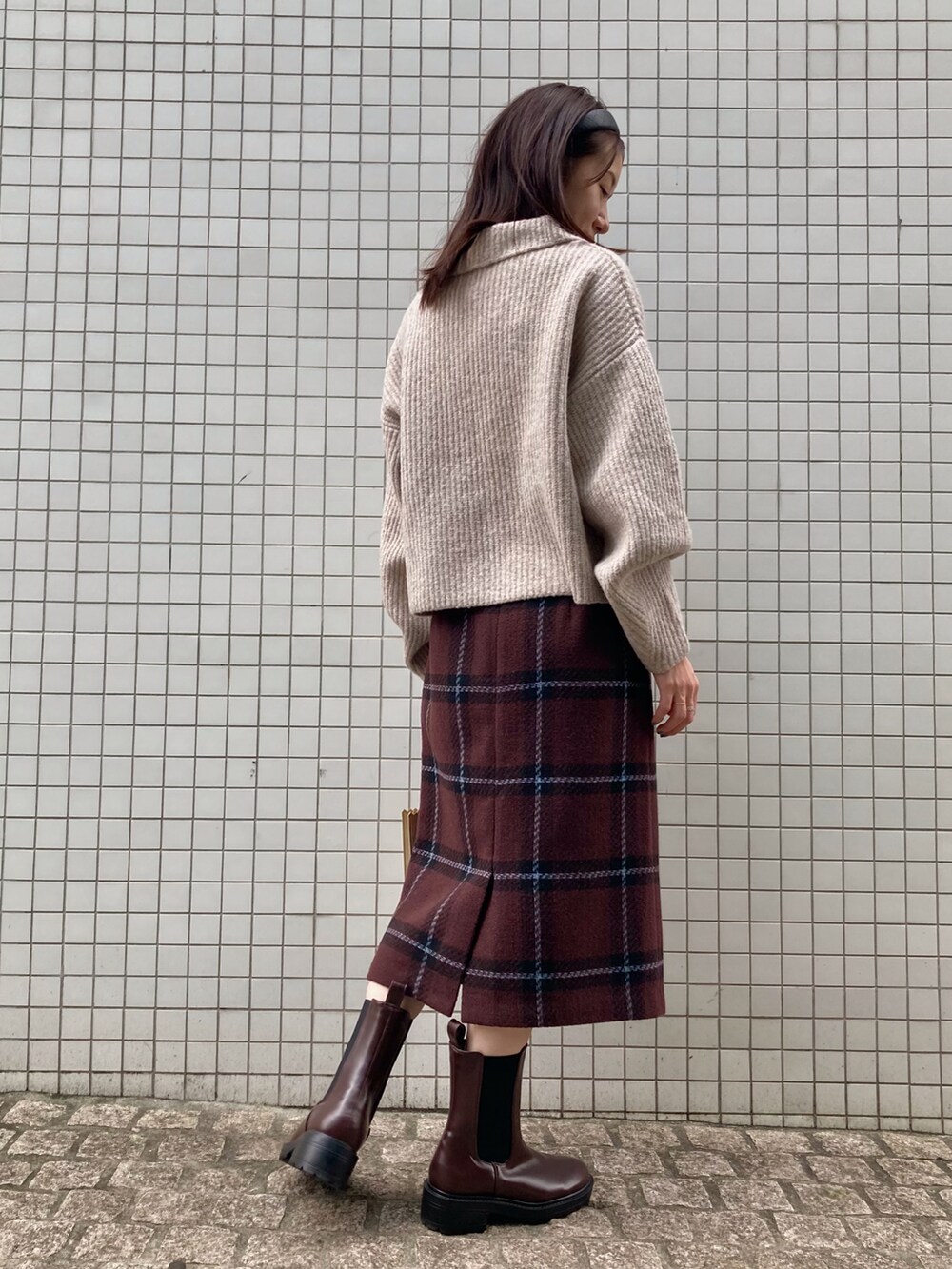 ベージュ系のニット/セーター、ゴールド系のトートバッグ、ブラウン系のブーツを着用したレディースの秋コーディネートの2枚目の写真