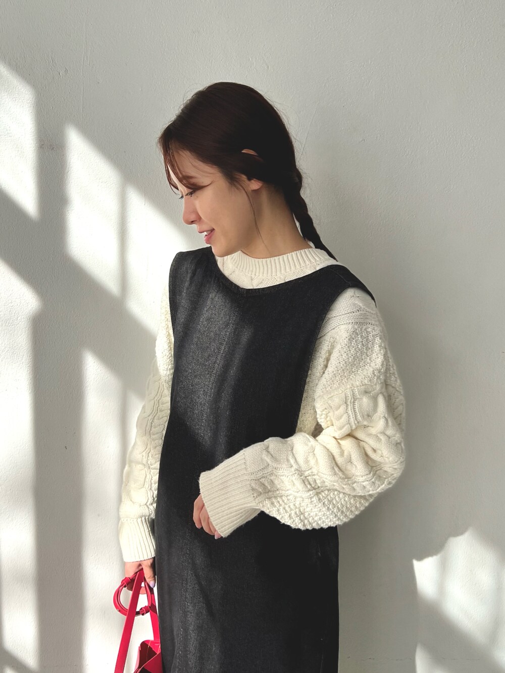 ブラック系のジャンパースカート、ホワイト系のニット/セーター、ピンク系のショルダーバッグを着用したレディースの冬コーディネートの4枚目の写真
