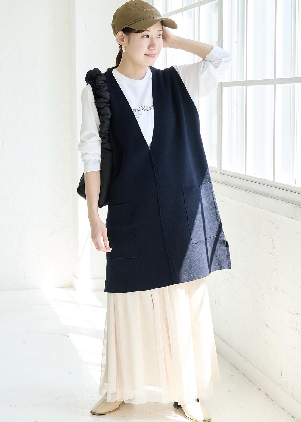 ベージュ系のスカート、ホワイト系のパンプス、ブルー系のベストを着用したレディースの秋コーディネートの2枚目の写真