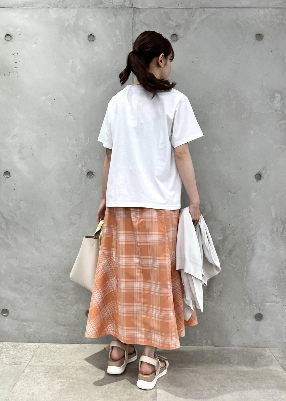 オレンジ系のスカート、グレー系のカーディガン/ボレロ、ホワイト系のTシャツ/カットソーを着用したレディースの春コーディネートの5枚目の写真