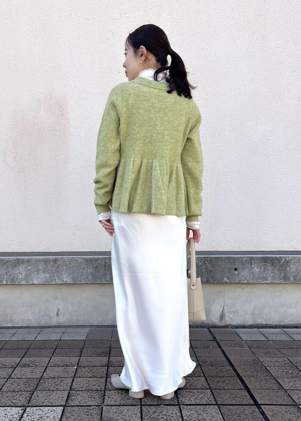 ホワイト系のスカート、グリーン系のニット/セーター、ベージュ系のパンプスを着用したレディースの冬コーディネートの6枚目の写真