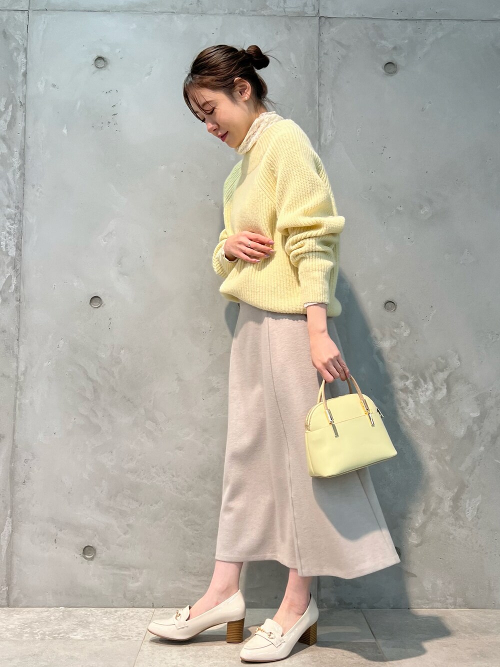 イエロー系のニット/セーター、ピンク系のスカート、イエロー系のボストンバッグを着用したレディースの冬コーディネートの3枚目の写真