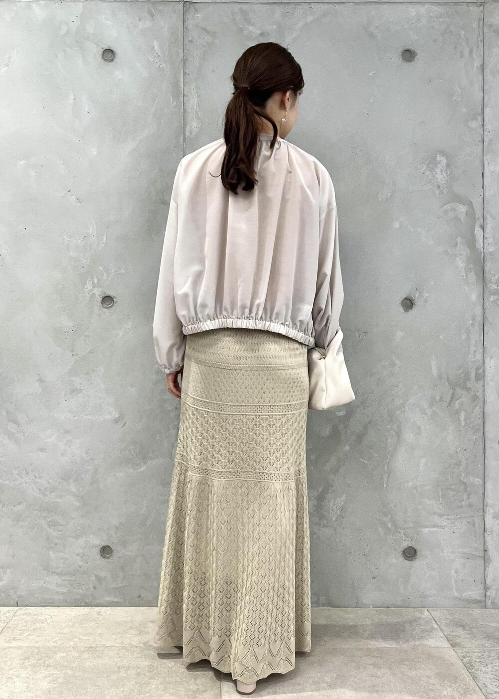 ベージュ系のサンダル、ベージュ系のブルゾン、オレンジ系のニット/セーターを着用したレディースの春コーディネートの3枚目の写真