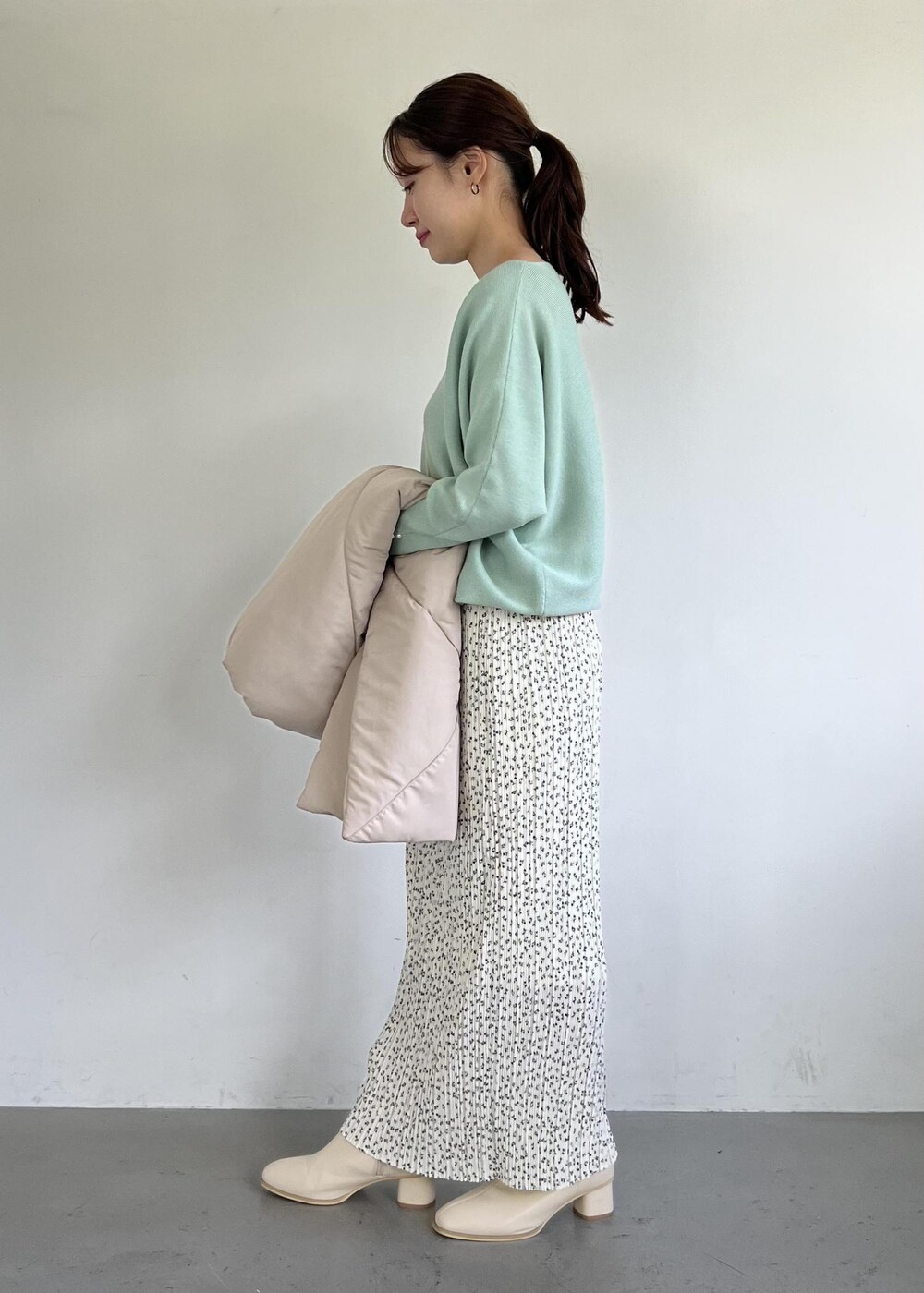 グリーン系のニット/セーター、ホワイト系のブーツ、ホワイト系のスカートを着用したレディースの秋コーディネートの2枚目の写真