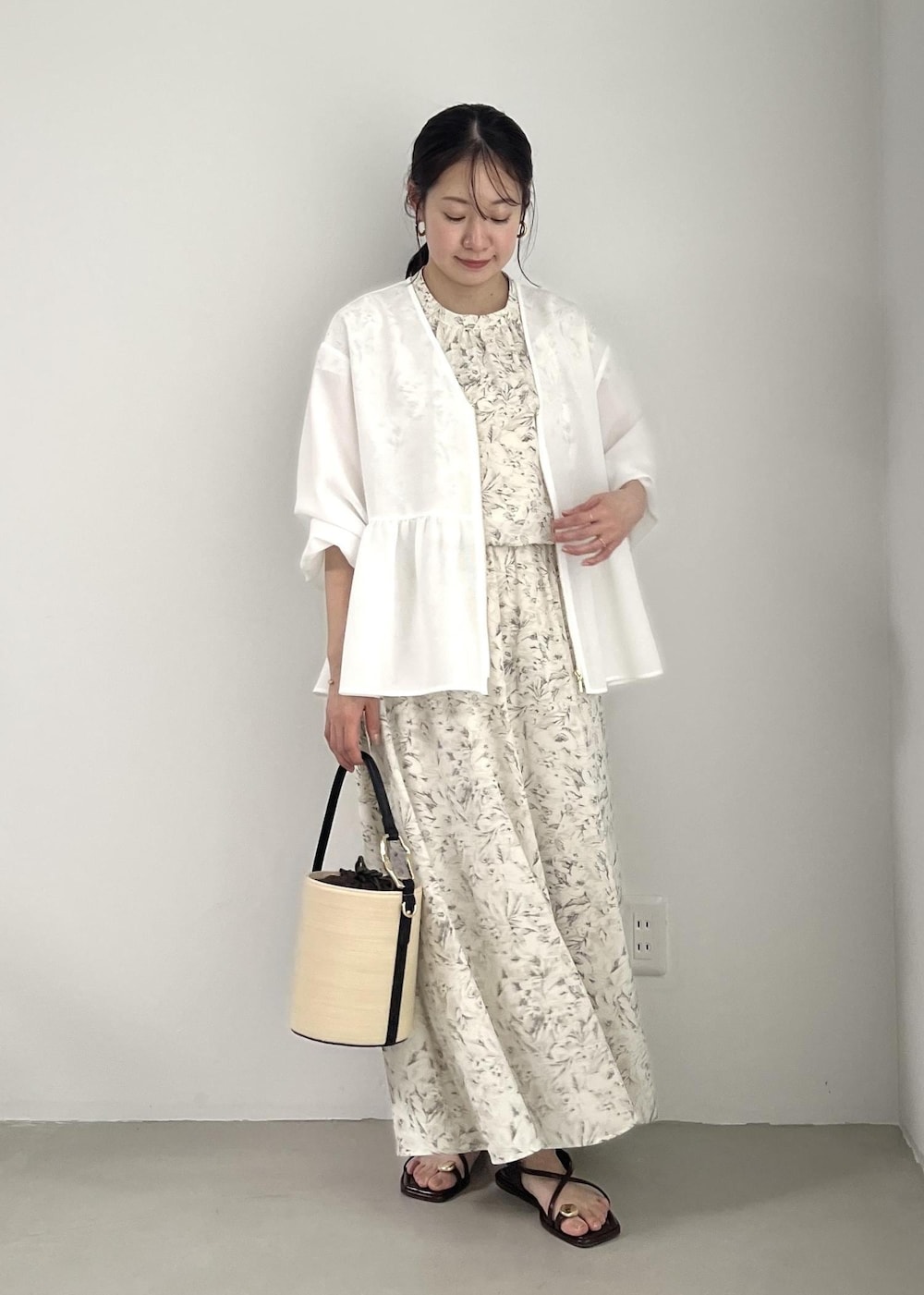 ホワイト系のブルゾン、ブラック系のサンダル、ホワイト系のワンピースを着用したレディースの春コーディネートの2枚目の写真