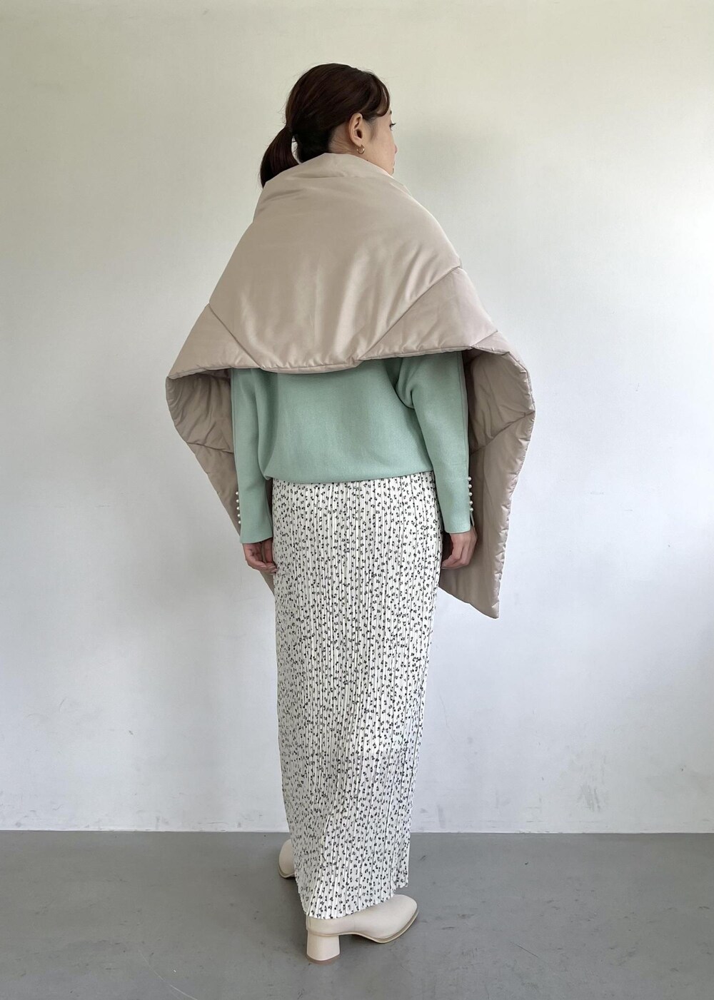 グリーン系のニット/セーター、ホワイト系のブーツ、ホワイト系のスカートを着用したレディースの秋コーディネートの3枚目の写真