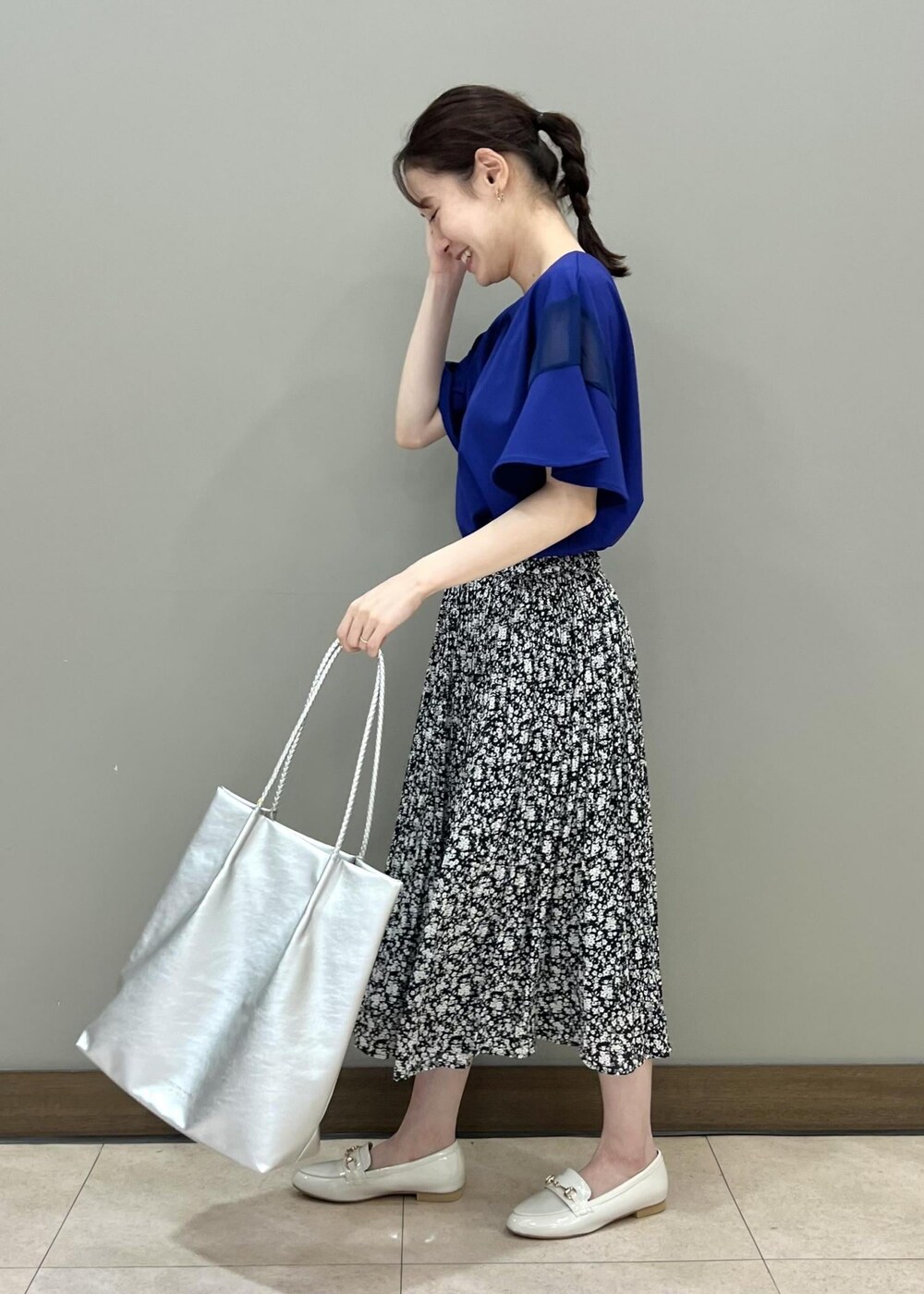 ホワイト系のローファー、シルバー系のトートバッグ、ブラック系のスカートを着用したレディースの夏コーディネートの2枚目の写真