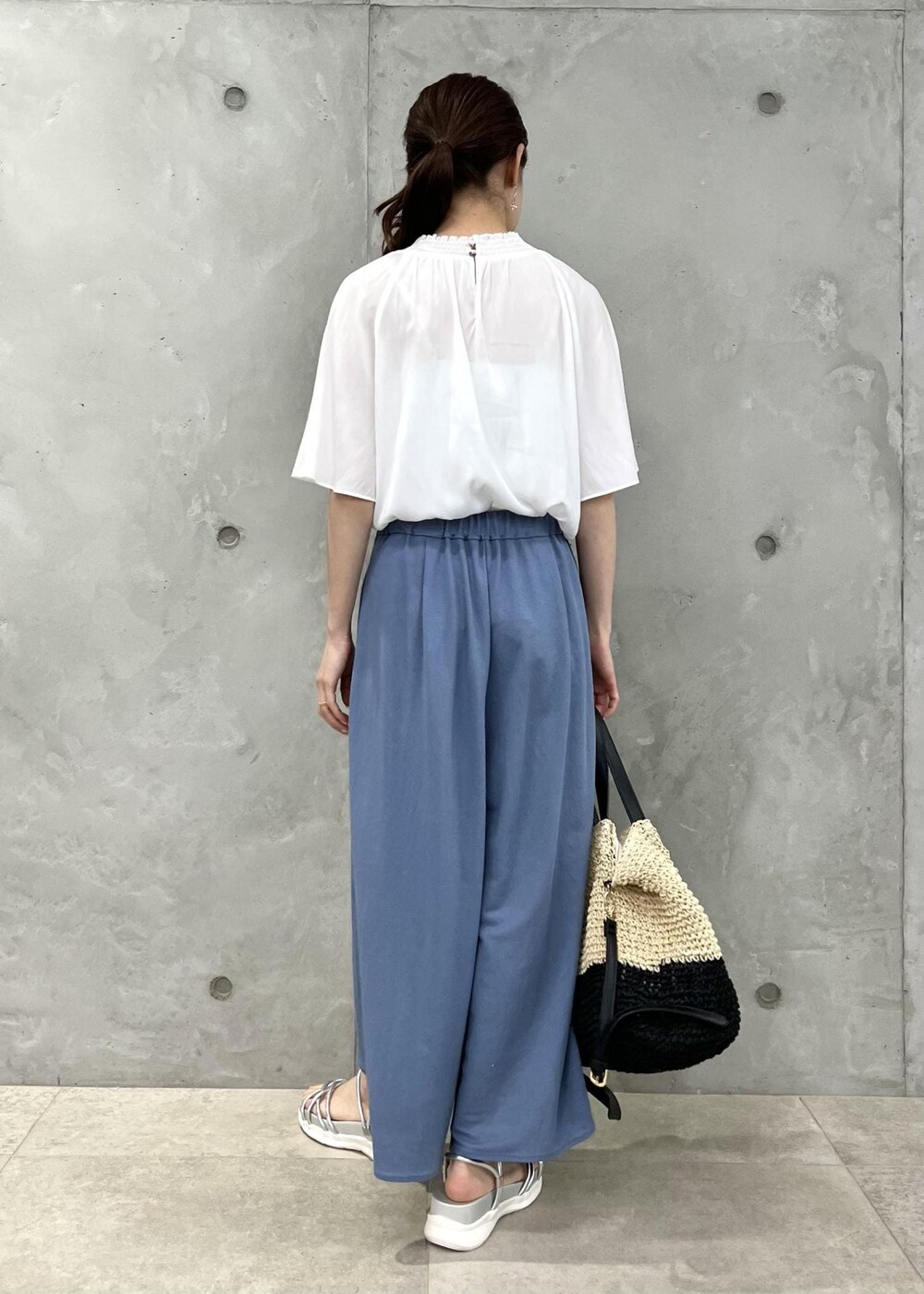 ブラック系のトートバッグ、シルバー系のサンダル、ホワイト系のシャツ/ブラウスを着用したレディースの夏コーディネートの3枚目の写真