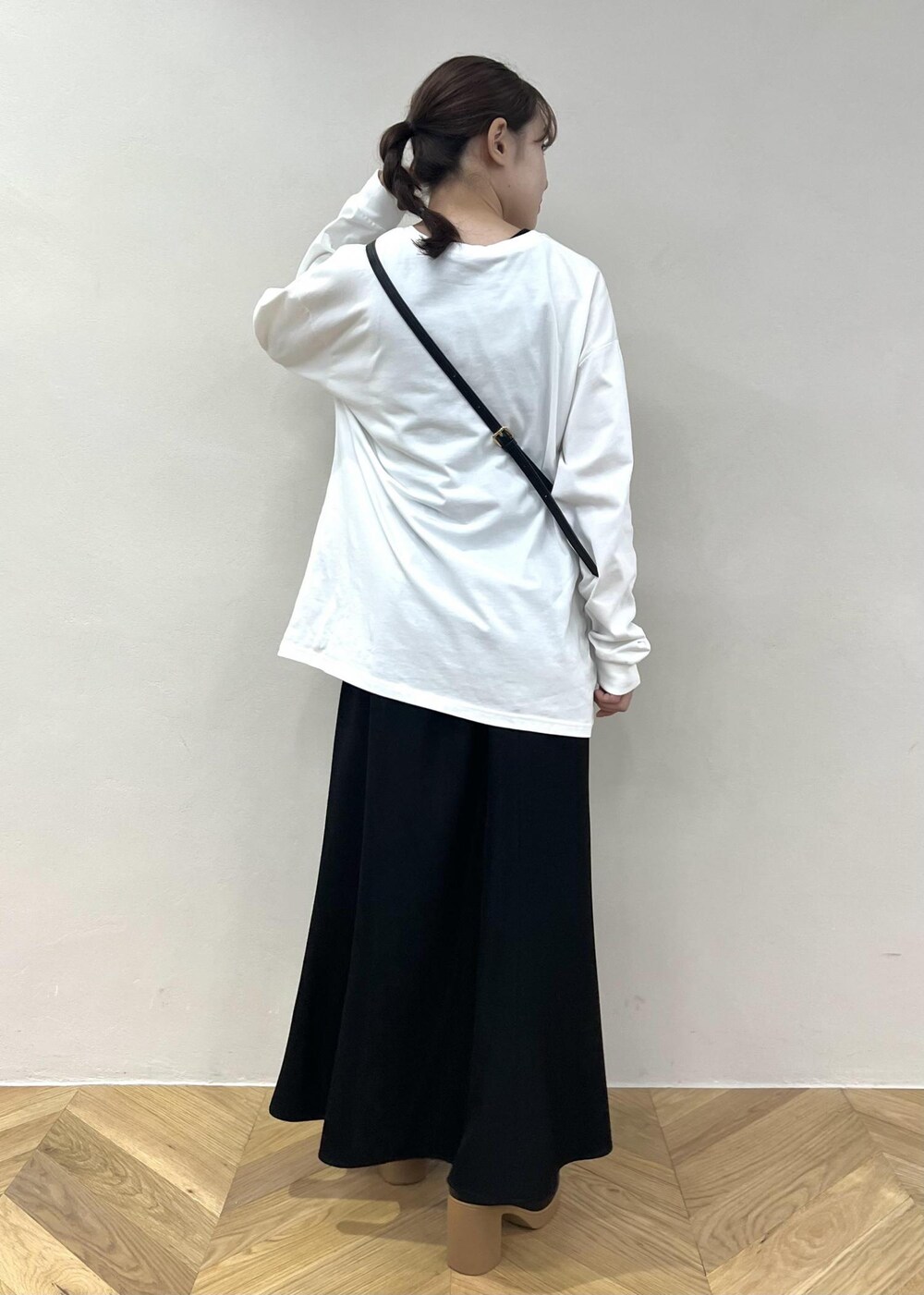 ブラック系のスカート、ホワイト系のTシャツ/カットソー、ブラック系のショルダーバッグを着用したレディースの秋コーディネートの3枚目の写真