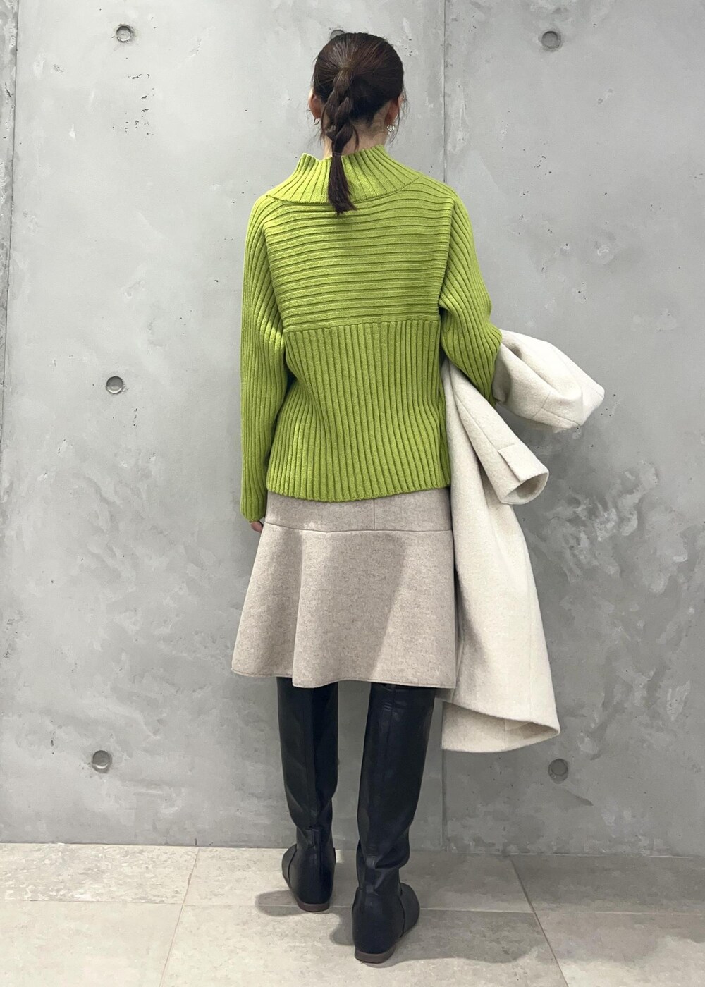 グリーン系のニット/セーター、ベージュ系のスカート、ホワイト系のその他アウターを着用したレディースの冬コーディネートの5枚目の写真