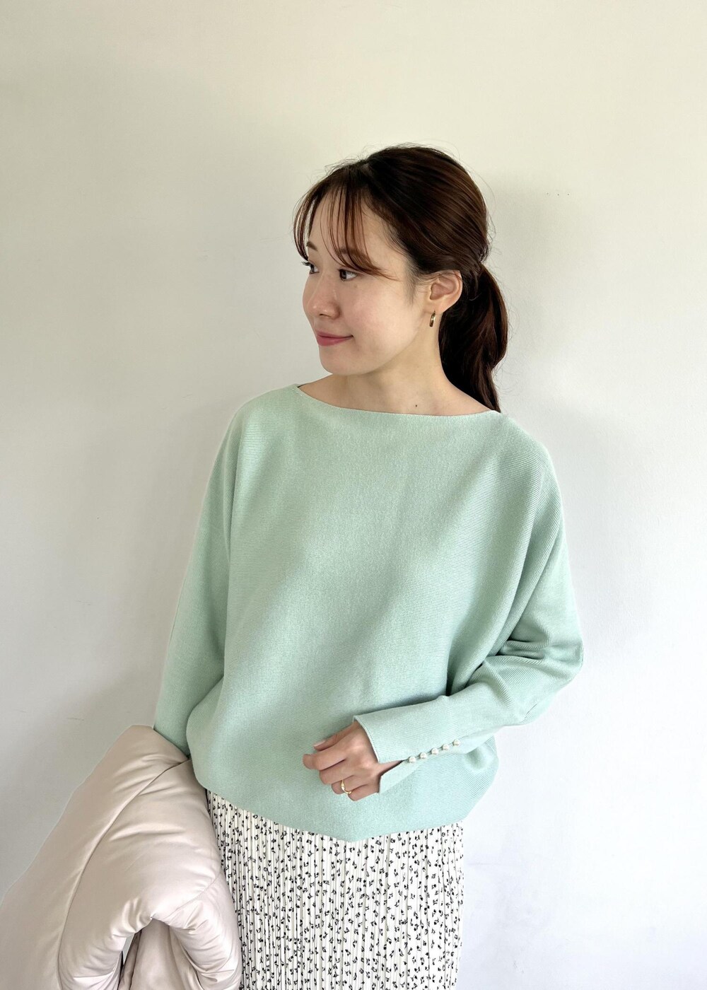 グリーン系のニット/セーター、ホワイト系のブーツ、ホワイト系のスカートを着用したレディースの秋コーディネートの4枚目の写真