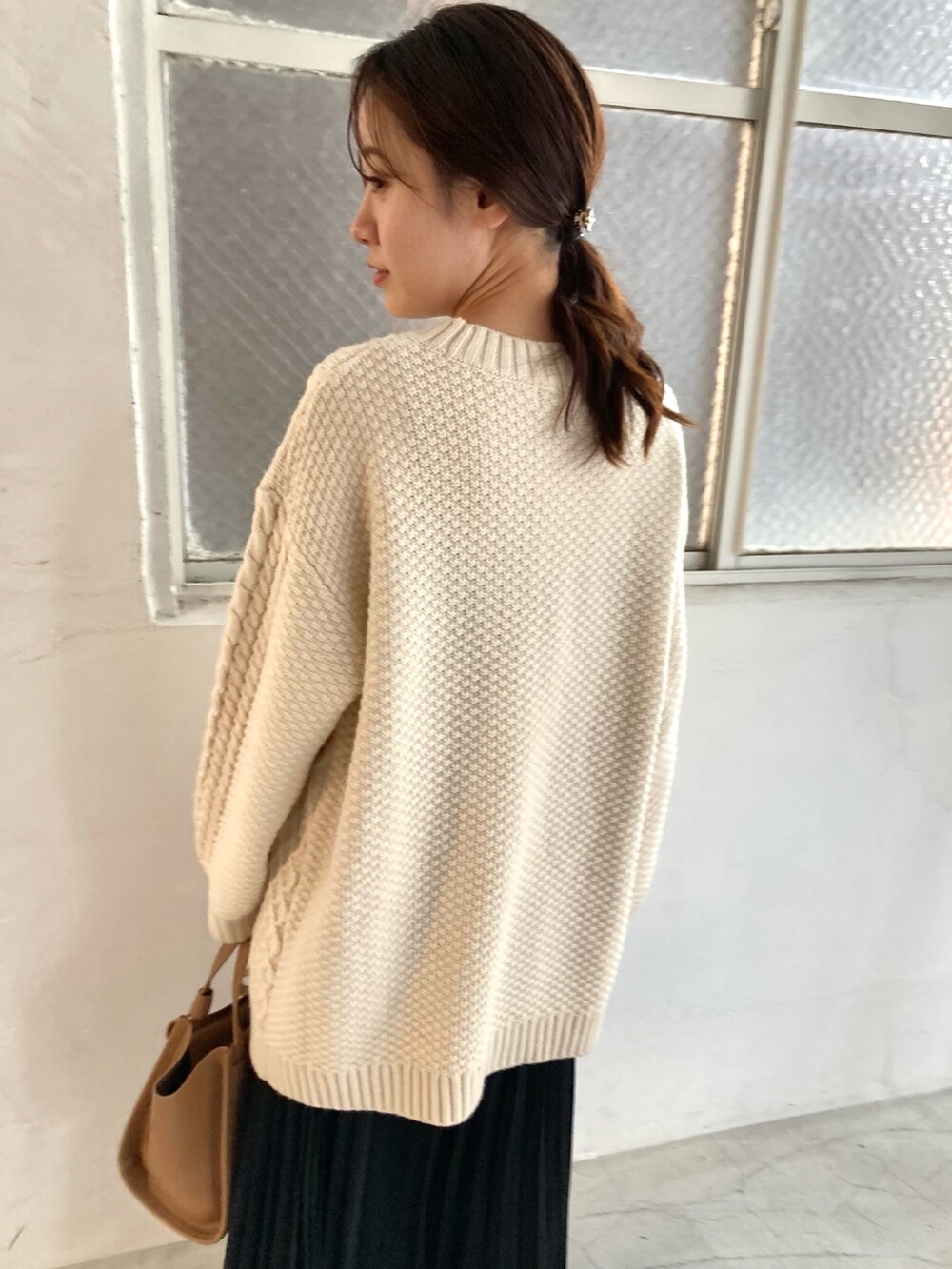 ホワイト系のニット/セーター、ブラック系のスカート、ブラック系のブーツを着用したレディースの冬コーディネートの3枚目の写真