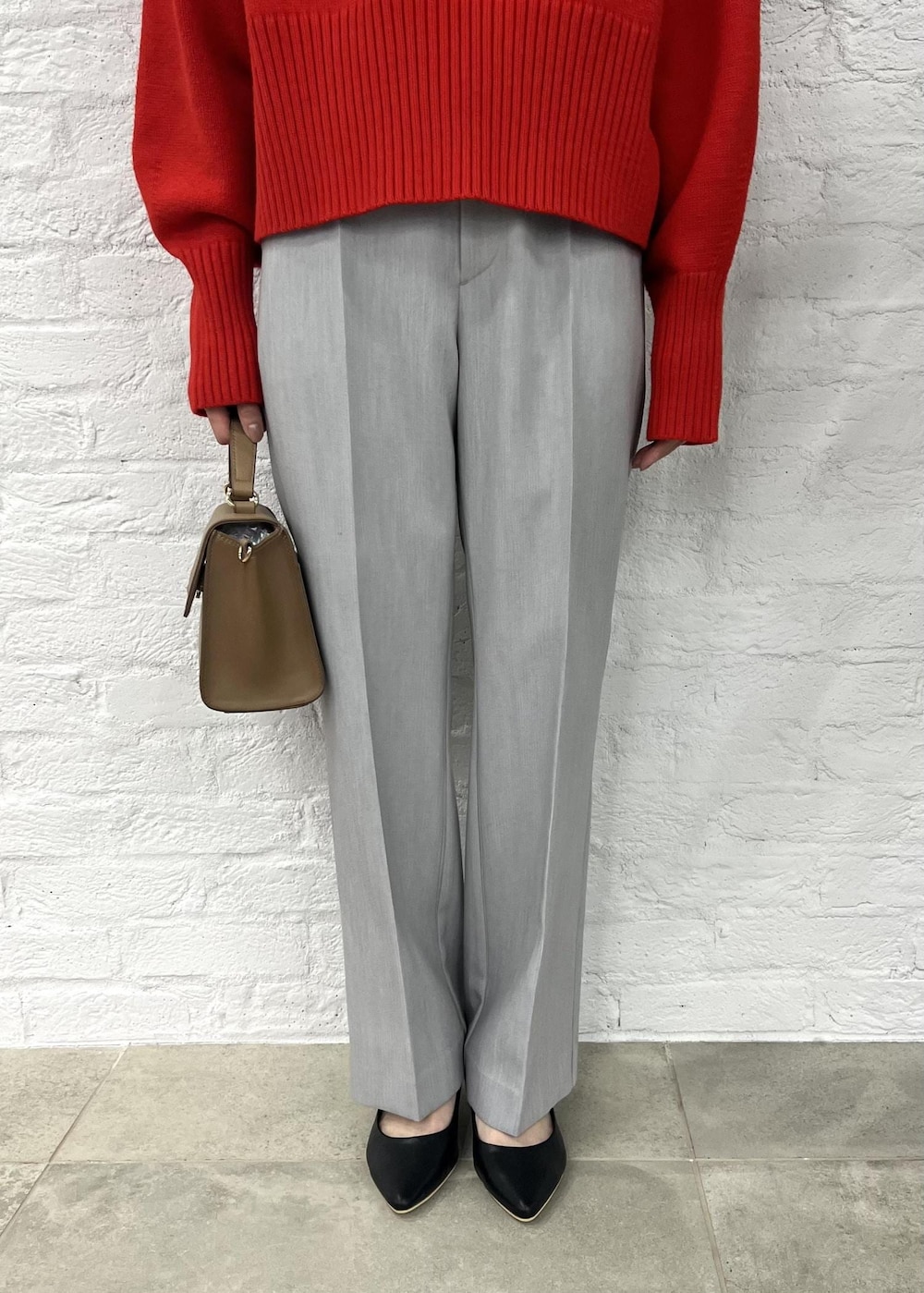 レッド系のニット/セーター、グレー系のその他パンツ、ブラック系のパンプスを着用したレディースの秋コーディネートの6枚目の写真