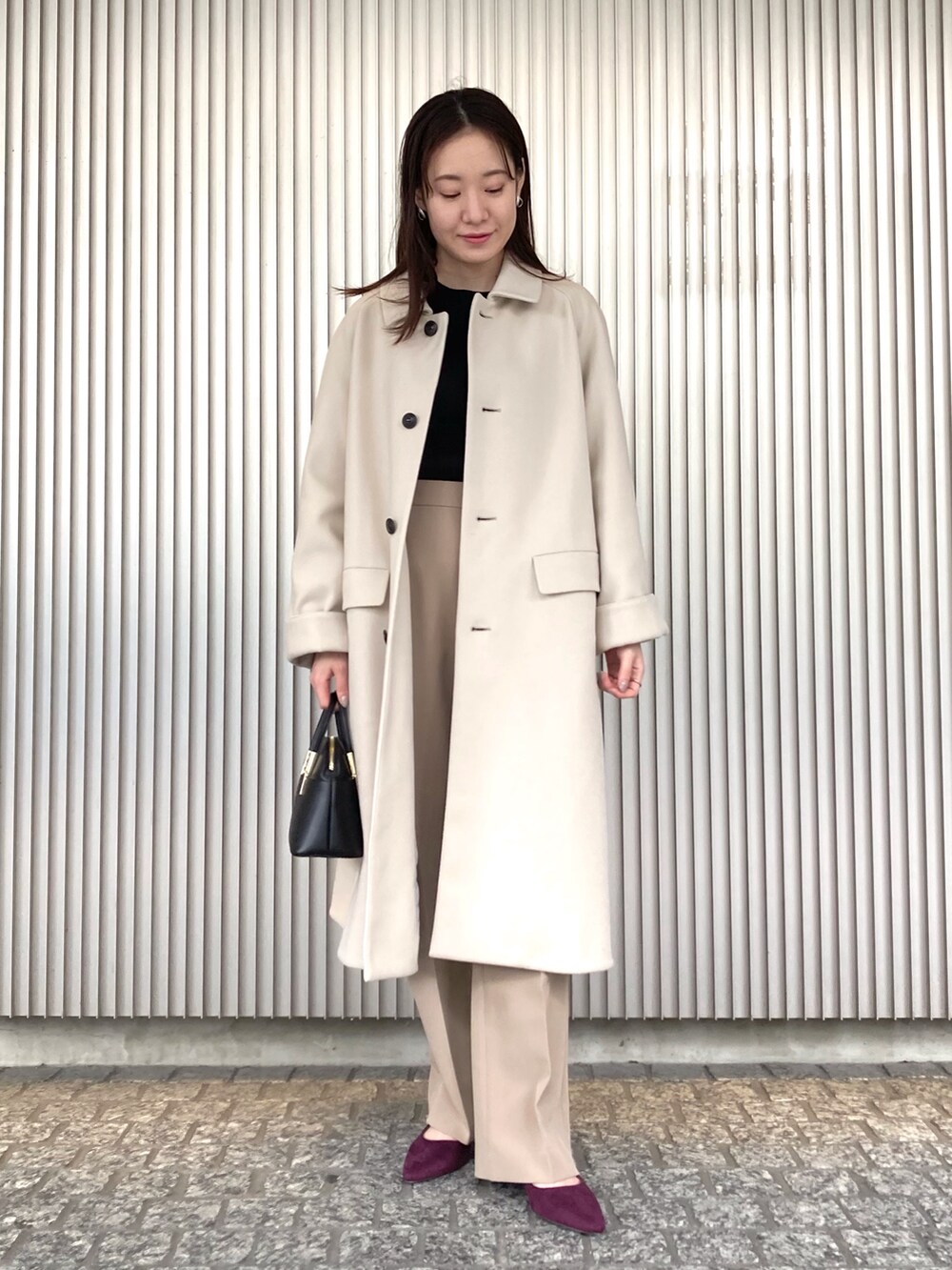 ブラック系のニット/セーター、ベージュ系のステンカラーコート、ブラック系のショルダーバッグを着用したレディースの秋コーディネートの2枚目の写真