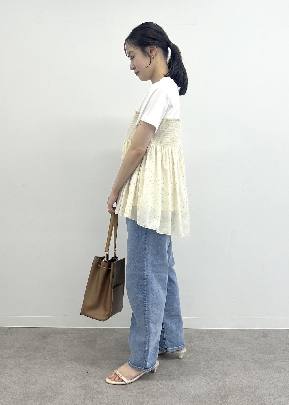 ブルー系のデニムパンツ、ブラウン系のショルダーバッグ、ブラック系のTシャツ/カットソーを着用したレディースの夏コーディネートの2枚目の写真
