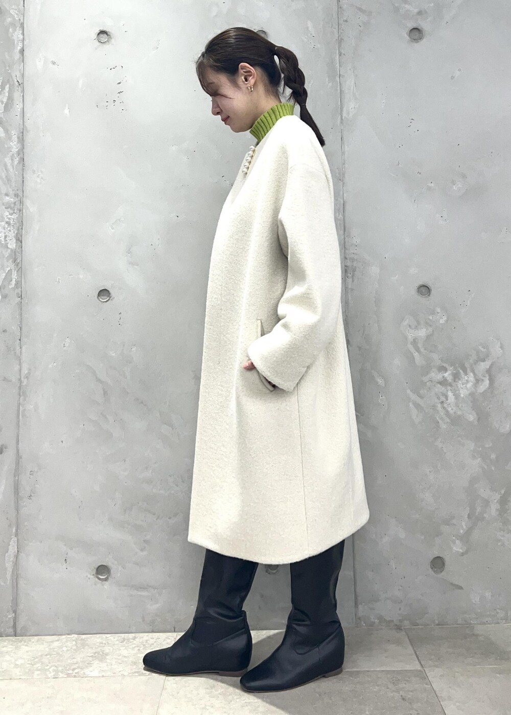 グリーン系のニット/セーター、ベージュ系のスカート、ホワイト系のその他アウターを着用したレディースの冬コーディネートの2枚目の写真