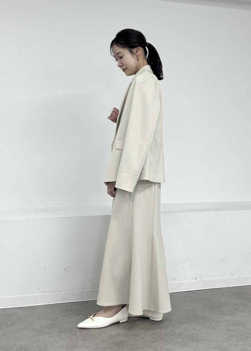 ホワイト系のパンプス、ベージュ系のテーラードジャケット、ベージュ系のスカートを着用したレディースの春コーディネートの2枚目の写真
