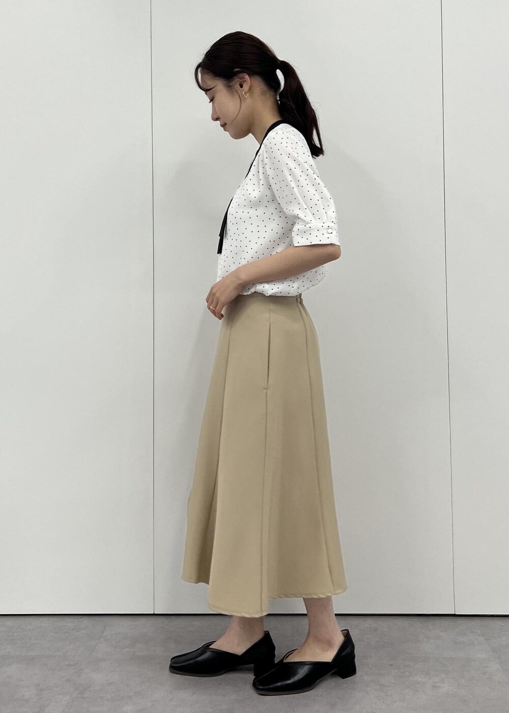 ベージュ系のショルダーバッグ、ベージュ系のスカート、ホワイト系のシャツ/ブラウスを着用したレディースの夏コーディネートの2枚目の写真