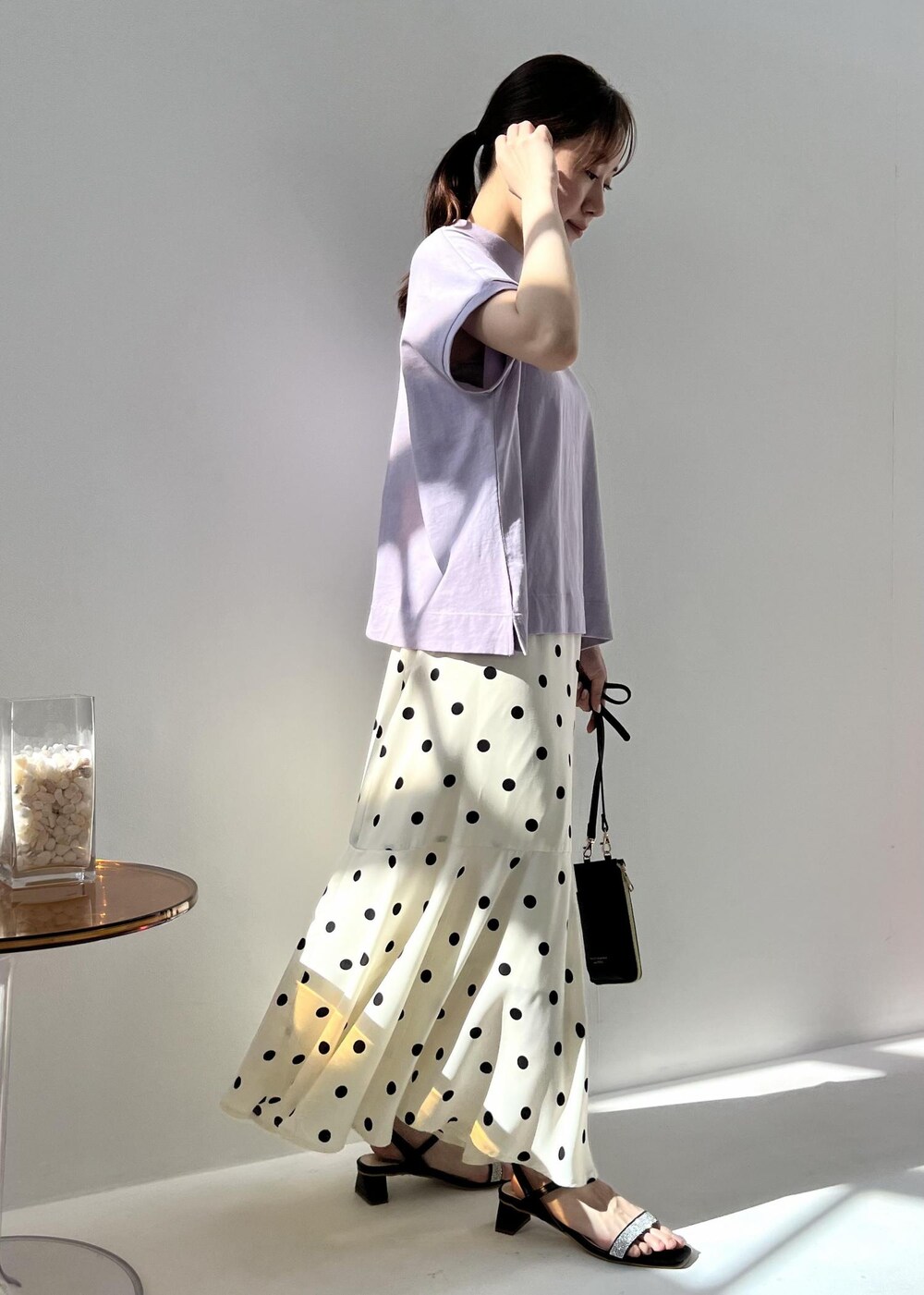 ブラック系のショルダーバッグ、パープル系のTシャツ/カットソー、ブラック系のサンダルを着用したレディースの春コーディネートの3枚目の写真