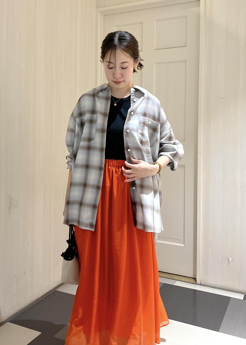 オレンジ系のスカート、ブラック系のタンクトップ、ブラック系のサンダルを着用したレディースの夏コーディネートの8枚目の写真