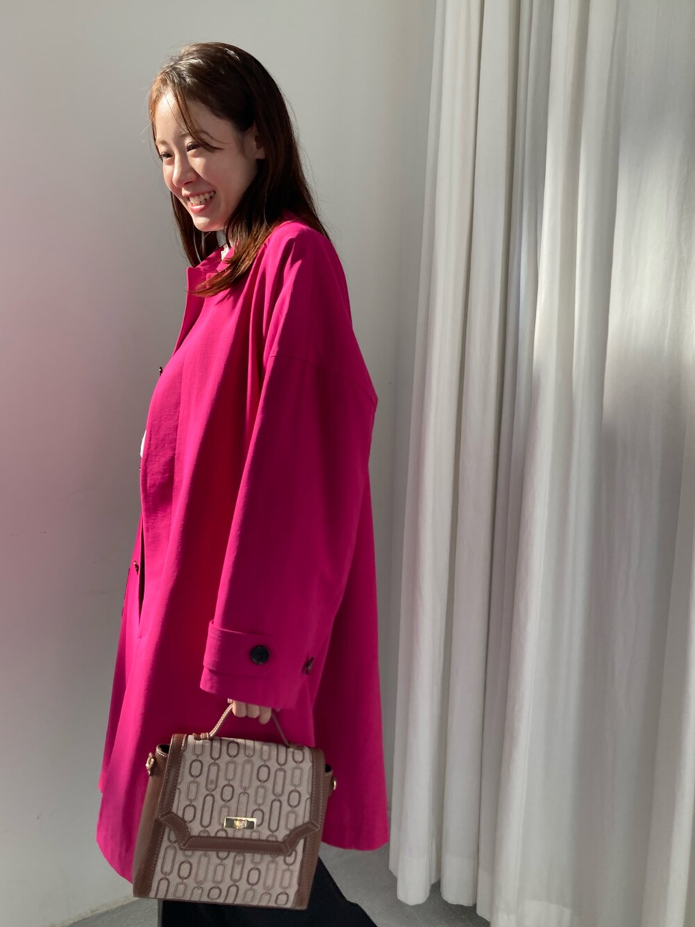 ピンク系のステンカラーコート、ブラウン系のショルダーバッグ、ブラック系のその他パンツを着用したレディースの冬コーディネートの5枚目の写真