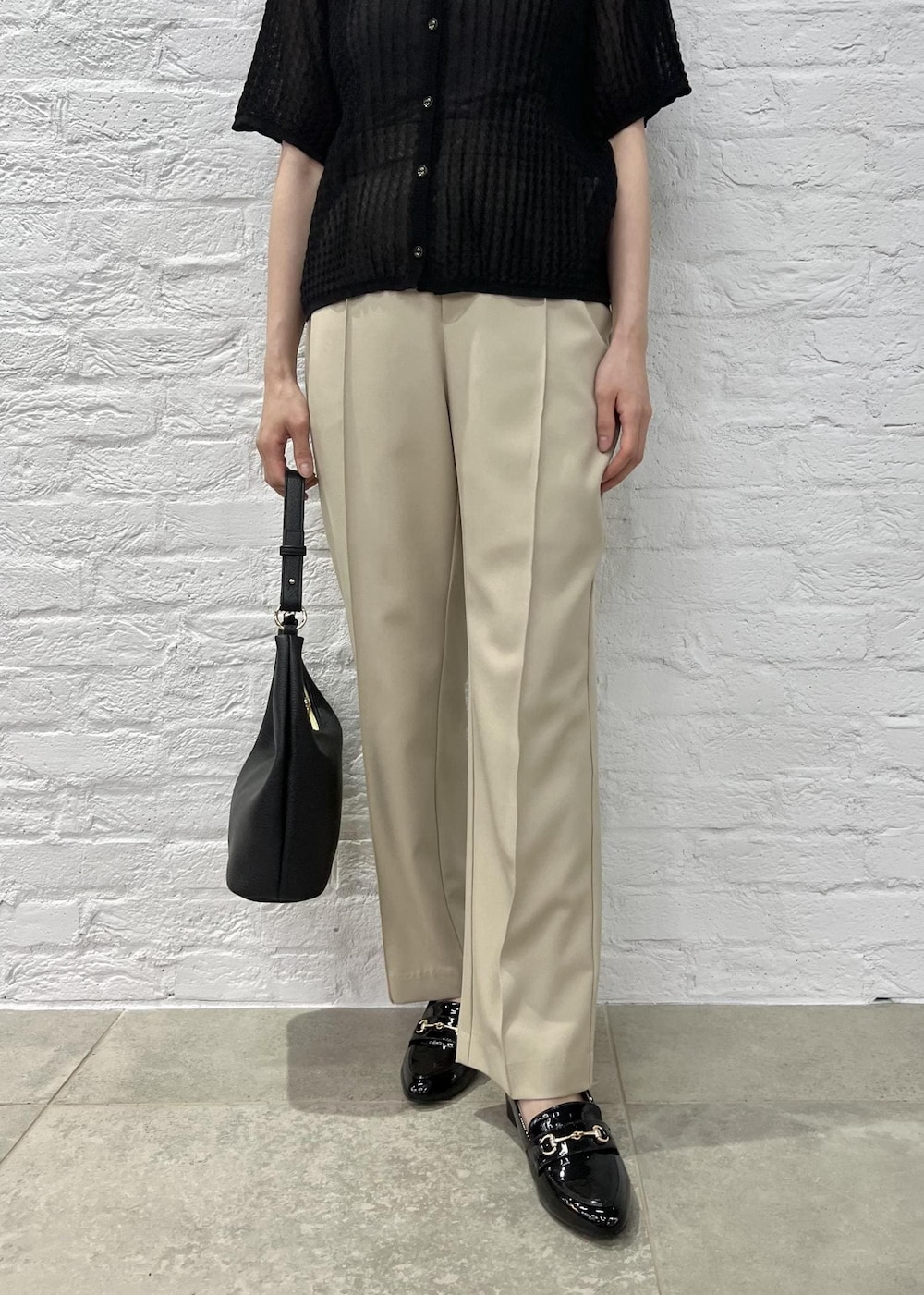 ブラック系のローファー、ブラック系のショルダーバッグ、ベージュ系のスラックスを着用したレディースの夏コーディネートの6枚目の写真